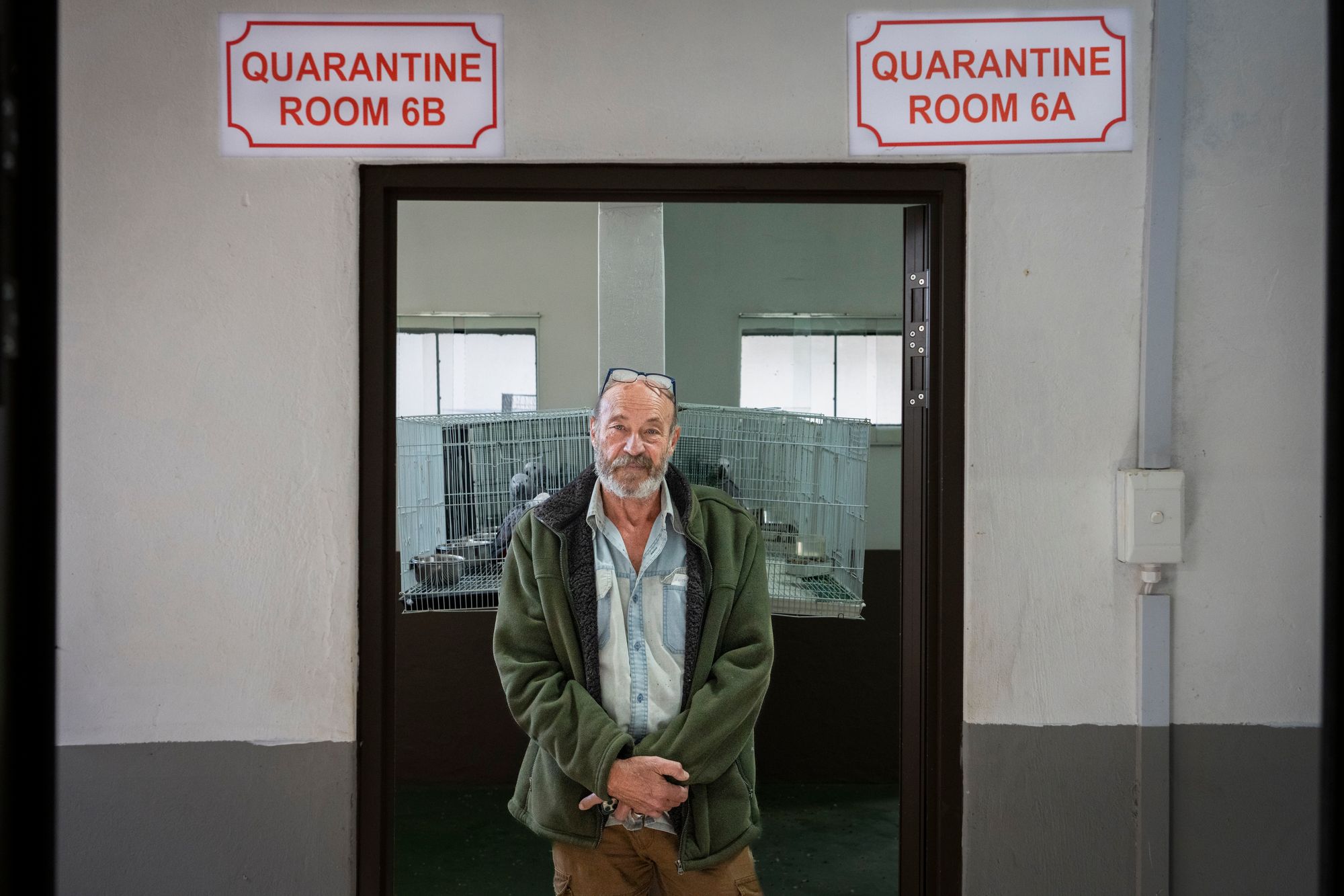 man standing in doorway with bird cages in background