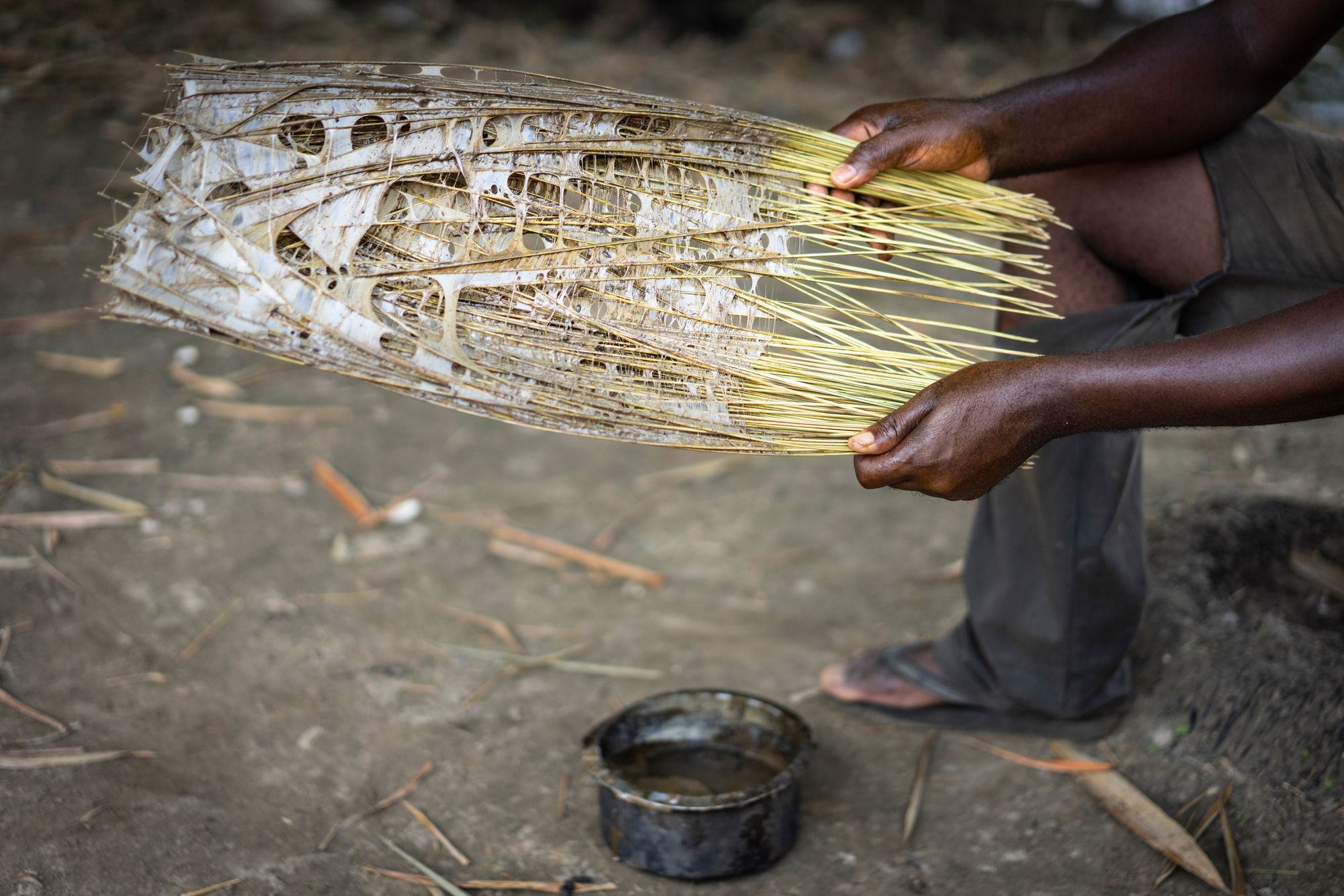 Close up of hands holding bunch of sticks with glue webbed between them